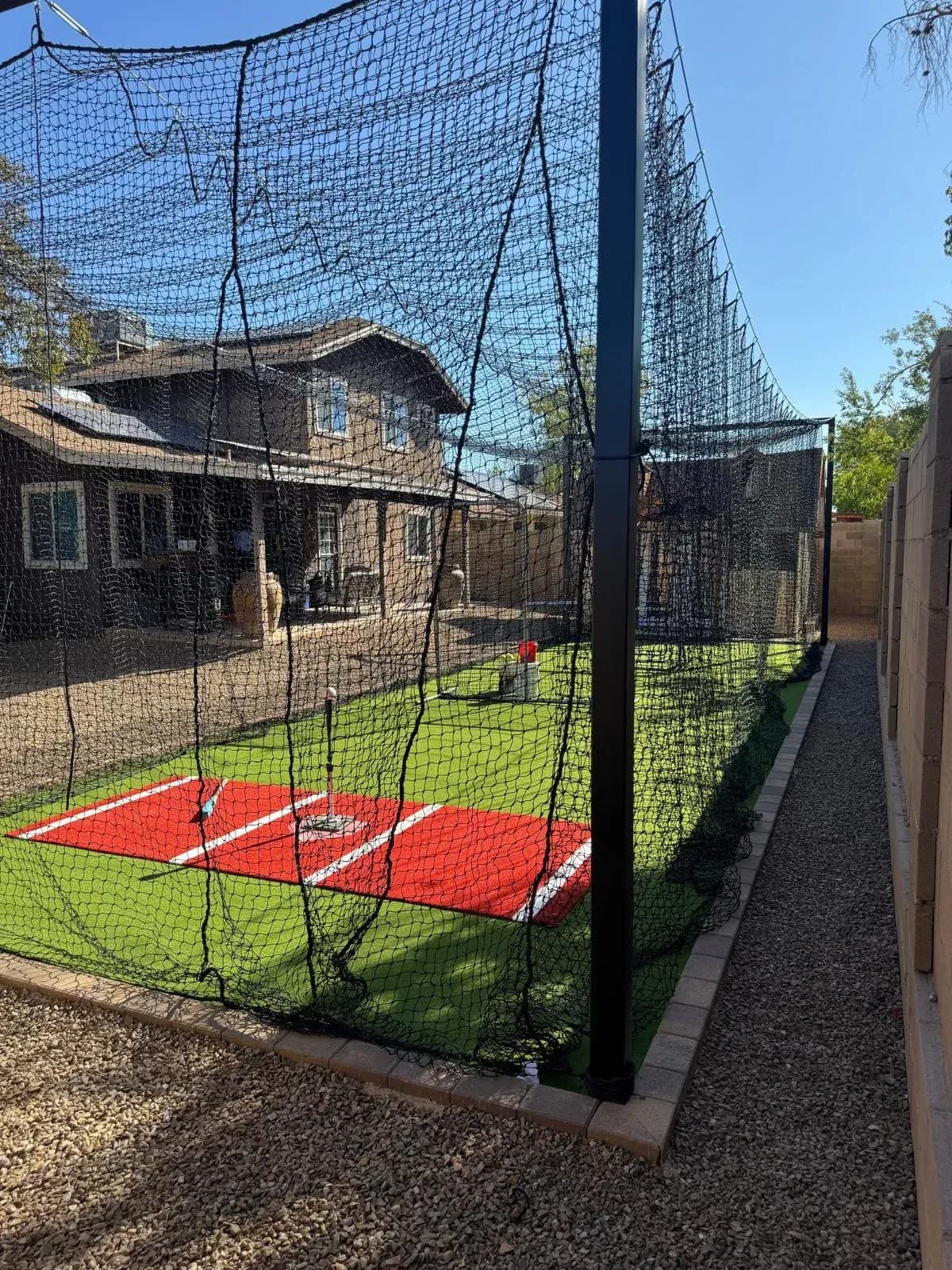 Backyard retractable batting cage over turf with mound and plate