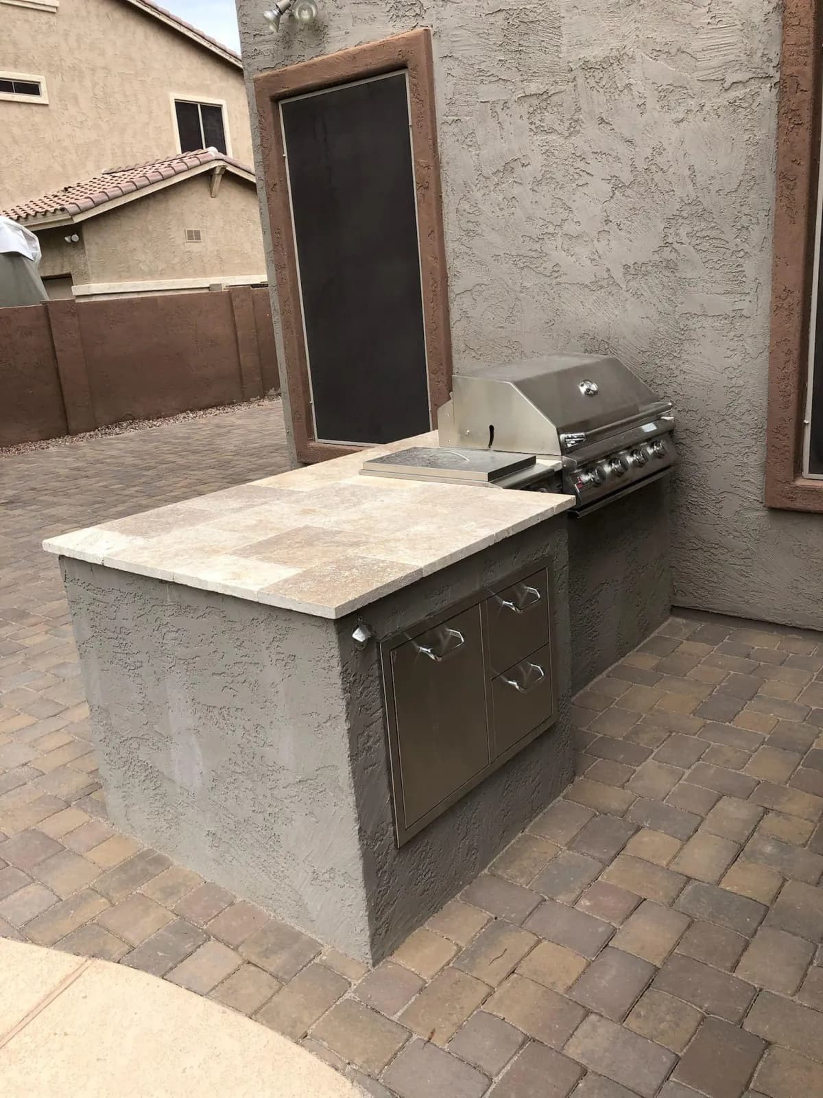 Built-in outdoor kitchen with travertine counter and stainless grill