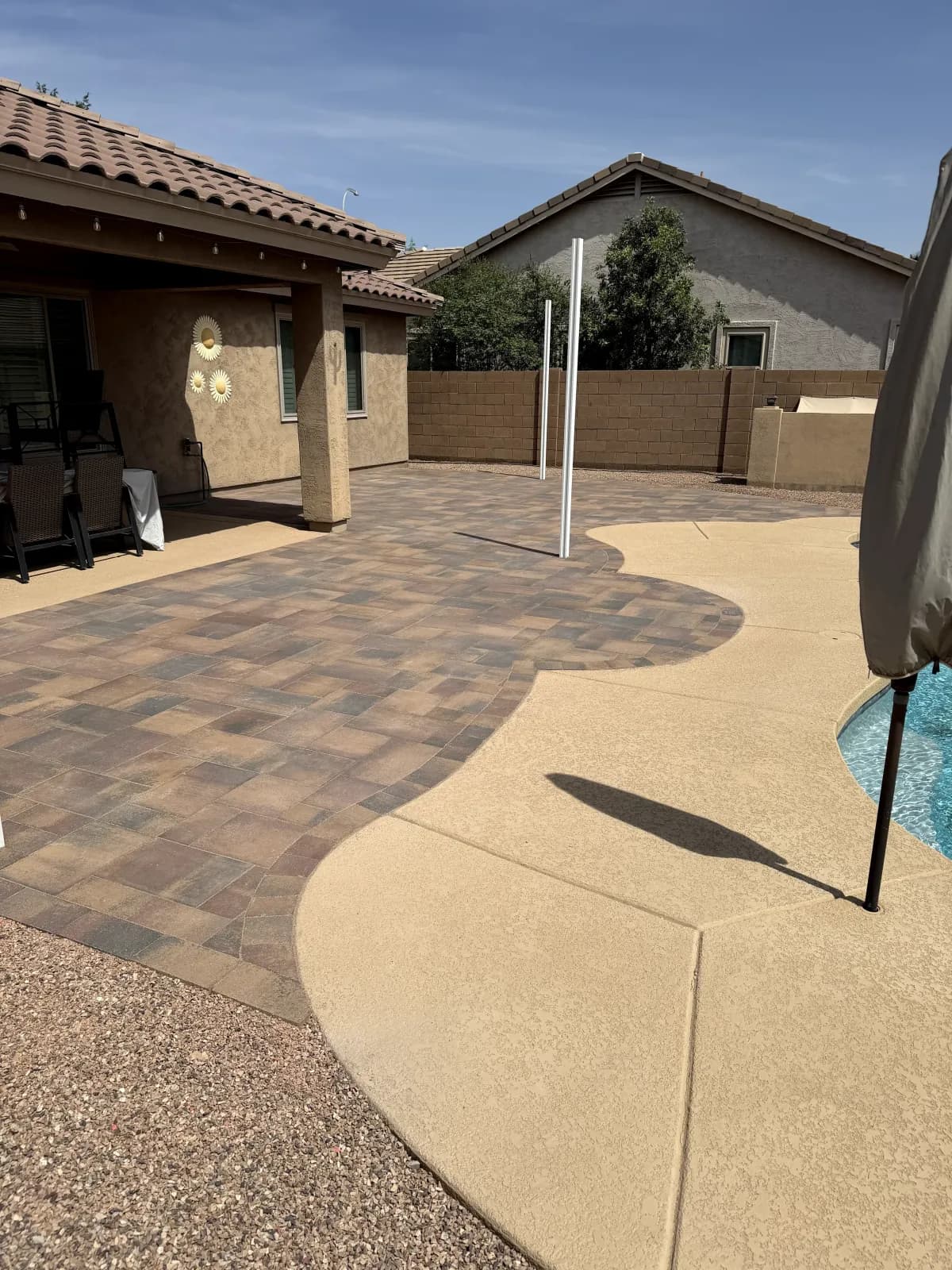 Custom curved paver patio wrapping a backyard pool deck
