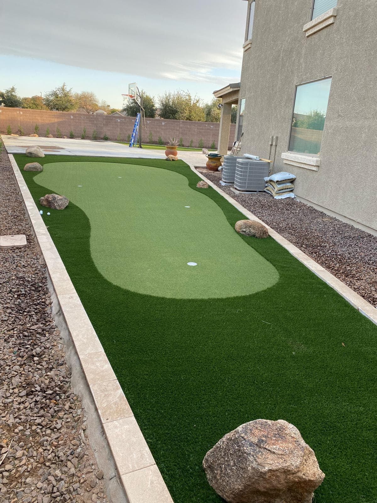 Backyard artificial putting green bordered with paver edging